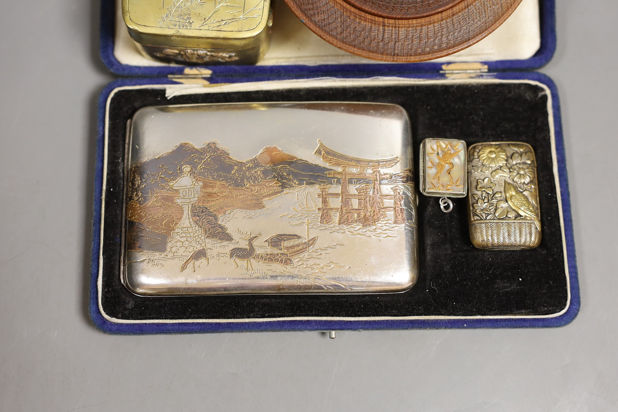 A Japanese sterling cigarette case, vesta, a locket, box and carved circular bowl and cover, bowl and cover 11 cms diameter.